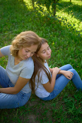 Fototapeta premium mother and teenage girls with long blond hair spend time together in the sunlit park