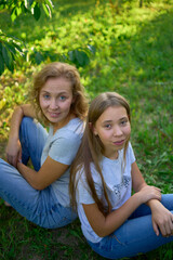 Fototapeta premium mother and teenage girls with long blond hair spend time together in the sunlit park
