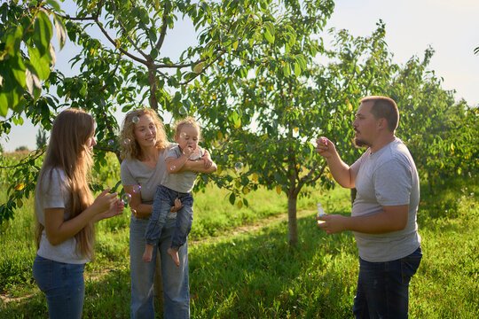 a family of four is playing catch bubbles in the garden