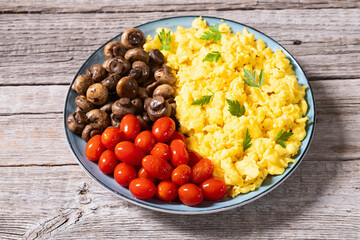 Homemade scrambled eggs with mushrooms and cherry tomatoes