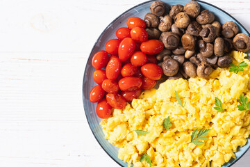 Homemade scrambled eggs with mushrooms and cherry tomatoes