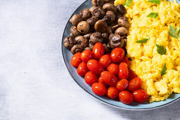 Homemade scrambled eggs with mushrooms and cherry tomatoes
