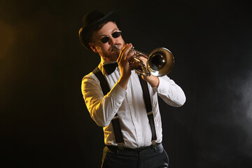 Professional musician playing trumpet on black background in color lights © New Africa
