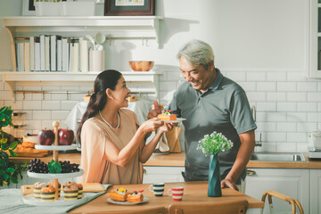 Two retired senior couples are tasting food they cooked together and laughing and chatting happily. Concept of health, retirement insurance, wealth accumulation, retirement society.