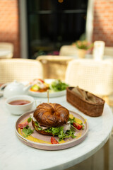 Fresh croissant sandwiches with vegetables, meat and cheese on a table with seeds and flour. Cup of aromatic tea in the background. High quality 