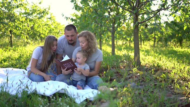 a  family reading the holy bible on a picnic in the garden