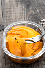 Marinated pumpkin slices in a glass bowl on wooden background