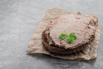 Liver meat pate spread on rye bread on gray background