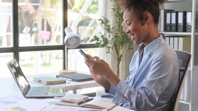 Young manager woman smiling while texting on smartphone at work