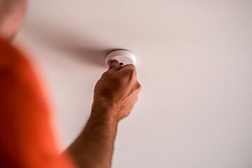 Fototapeta premium Male and Female Adults Installing Smoke Detectors in Homes and Public Buildings for Fire Prevention During the Day