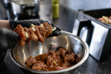 Threading a kebab on a skewer. Shish kebab in air fryer. Pieces of marinade meat in air fryer with onions.
