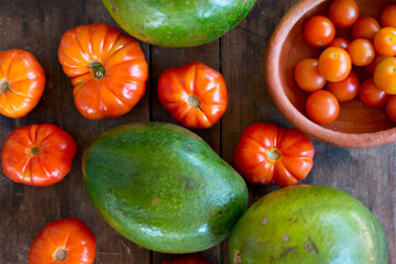 The geometry of nature: Margarita Island tomatoes and avocados are arranged on wood, creating an attractive visual pattern and a promise of fresh and delicious flavors, ready to be enjoyed.