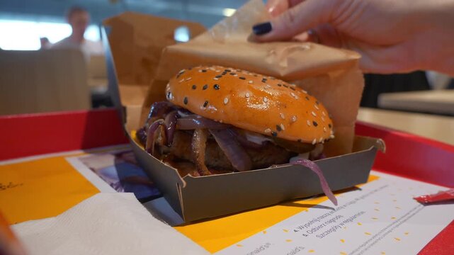 famous fast food restaurant girl hands open burger box on table slow motion panorama 4k poland