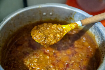 A spoon of porridge palm oil beans dished from a pot