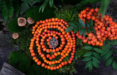 protective rowanberry spiral with pentacle amulet in forest, natural background. Magic ritual,...