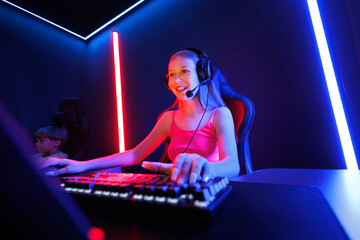 A young female streamer is looking at a computer monitor, a purple-blue LED is on.