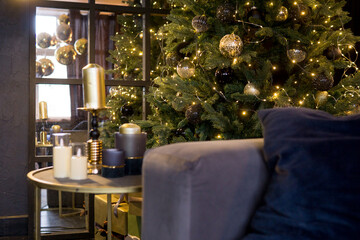 Christmas interior with a beautiful Christmas tree, sofa, light bulbs and dark background.