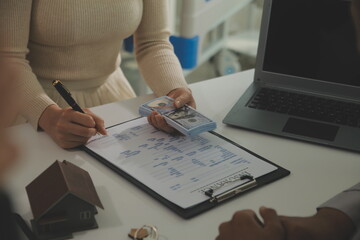 Real estate agent home sales broker is using a pen pointing to the house model and explains the business contract, rent, buy, mortgage, loan, or home insurance