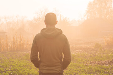 Back portrait of a man enjoying a beautiful autumn foggy in the countryside