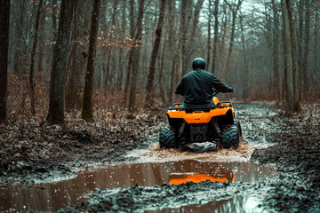 Person riding an orange ATV through a muddy trail in a forest on a cloudy day