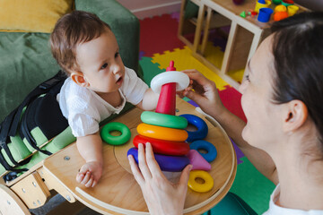 Mother spending useful time with her son with movement disorders playing developmental games while he stands in the rehabilitation verticalizer at home
