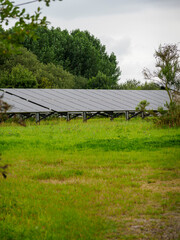 Solar panels installed in a lush green field with cloudy skies, promoting renewable energy and environmental sustainability.