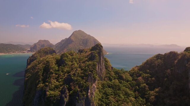 Establishing aerial view of tropical paradise exotic island surrounded by crystal blue sea and sail boats. Travel video of Bukal island El Nido Philippines, untouched nature on sunny summer day