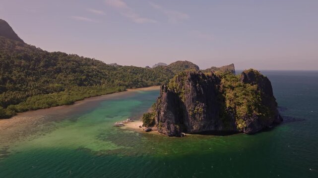 Establishing aerial view of tropical paradise exotic island surrounded by crystal blue sea and sail boats. Travel video of Bukal island El Nido Philippines, untouched nature on sunny summer day