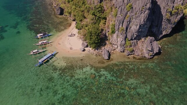 Establishing aerial view of tropical paradise exotic island surrounded by crystal blue sea and sail boats. Travel video of Bukal island El Nido Philippines, untouched nature on sunny summer day