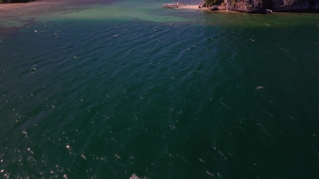 Aerial reveal shot of tropical paradise exotic island surrounded by crystal blue sea and sail boats. Travel video of Bukal island El Nido Philippines, untouched nature on sunny summer day
