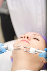 Fototapeta premium Dermatology anti age treatment. Microcurrent medicine procedure. Woman skin care. Aesthetic peeling therapy. RF equipment. Cosmetology device at spa. Doctor hands in gloves. Wrinkle reduction