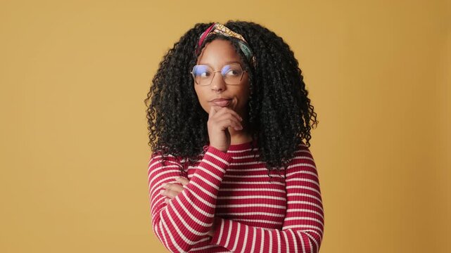 Confused woman cannot make choice on yellow background in the studio