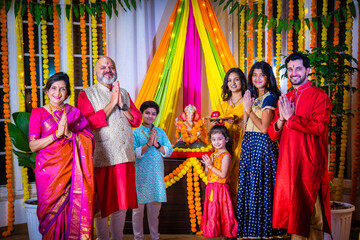 Indian Asian family performing Ganesh Puja at home in traditional attire, celebrating with devotion