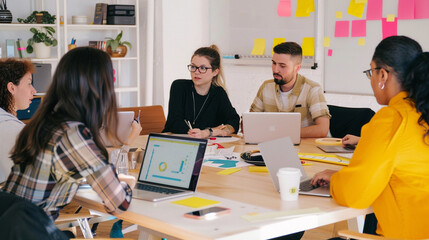 Fototapeta premium A diverse team of young tech entrepreneurs brainstorming ideas in a modern, colorful co-working space, with laptops, whiteboards, and coffee cups on the table