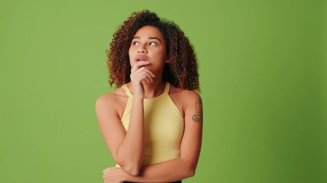 Woman thinking on a green screen background, makes a decision, doubts and doesn't know the answer
