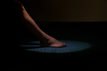 Obraz premium Boy's feet bare on the floor in the bedroom in a circle of light on the carpet and it's dark around, child's feet