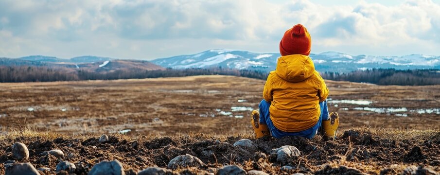 A child gazing over a barren landscape, representing the effects of climate change on future generations