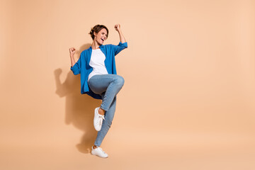 Full length photo of successful businesswoman in blue shirt raised fists up celebrate victory concurrent isolated on beige color background