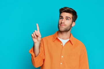Stylish man in orange shirt pointing to blank space on blue background   portrait photography