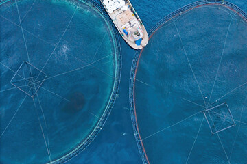Service boat for feeding fish on offshore aquafarming fish farm in sea for cultivation fish, aerial view