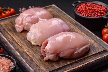 Fresh chicken fillet on a dark concrete table with spices and herbs