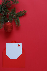 A pine branch on a red background with red envelope and red Christmas decorations.