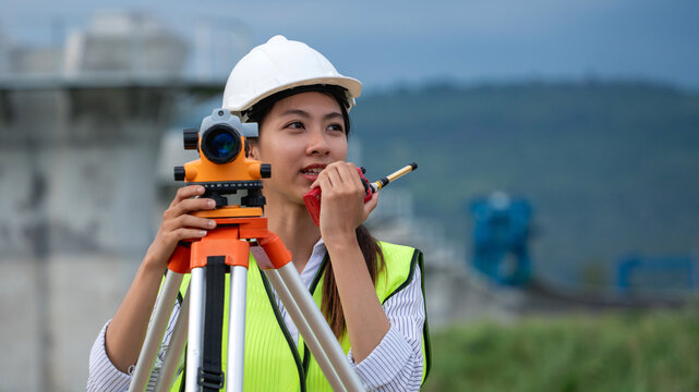 Construction workers wearing a safety vest and a hard hat is holding a surveying instrument