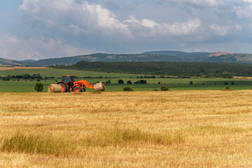 Fototapeta premium Tractor lifting hay bale on barrow.
