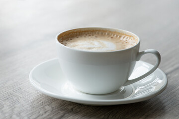Cup of hot cappuccino coffee on table