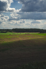 Obraz premium Thick clouds over green fields. The highway is far beyond the field