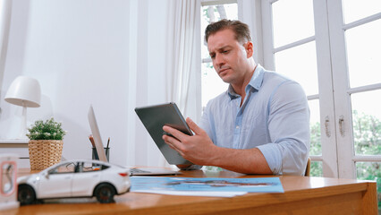 Stressed and frustrated car design engineer put his head in his hand after discover flaw in vehicle design, working at home for automotive business while trying to find solution. Synchronos