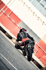 motorcyclist riding at high speed on an urban road, a person in motorcycle gear next to an off-road bike, and a racer leaning into a turn on a track