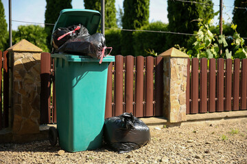Trash bags full of garbage and bin outdoors