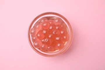 Bright tapioca pearls in bowl on pink background, top view